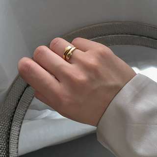 Close-up of Hug Ring in gold on a woman's hand, complementing a modern outfit